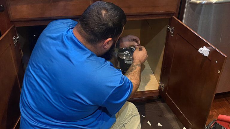 technician in blue shirt installing a garbage disposal