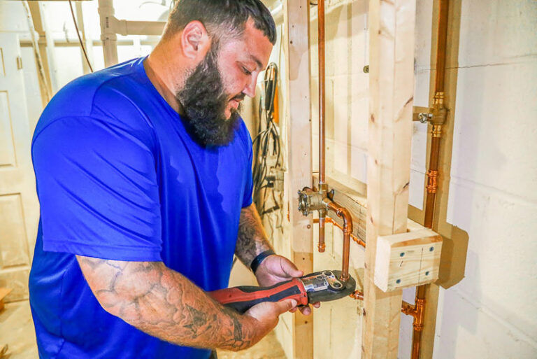 technician in blue shirt repairing copper pipes