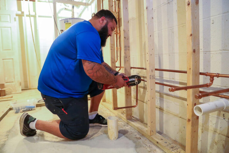 technician in blue shirt repairing copper pipes