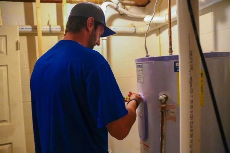 technician in blue shirt repairing water heater