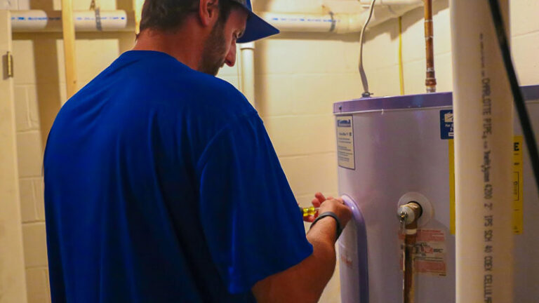 technician in blue shirt repairing water heater